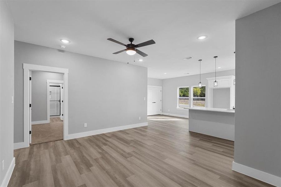 Unfurnished living room with light wood-type flooring and ceiling fan