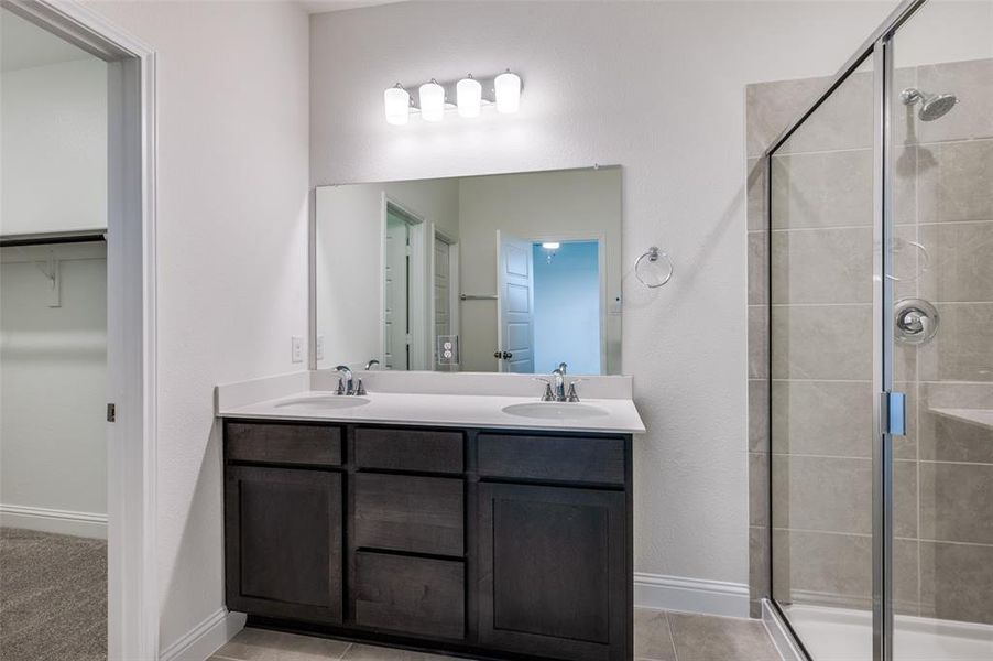Full bathroom featuring a stall shower, double vanity, and a walk in closet