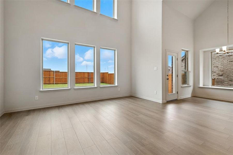 Unfurnished living room featuring a chandelier, a towering ceiling, and light wood finished floors