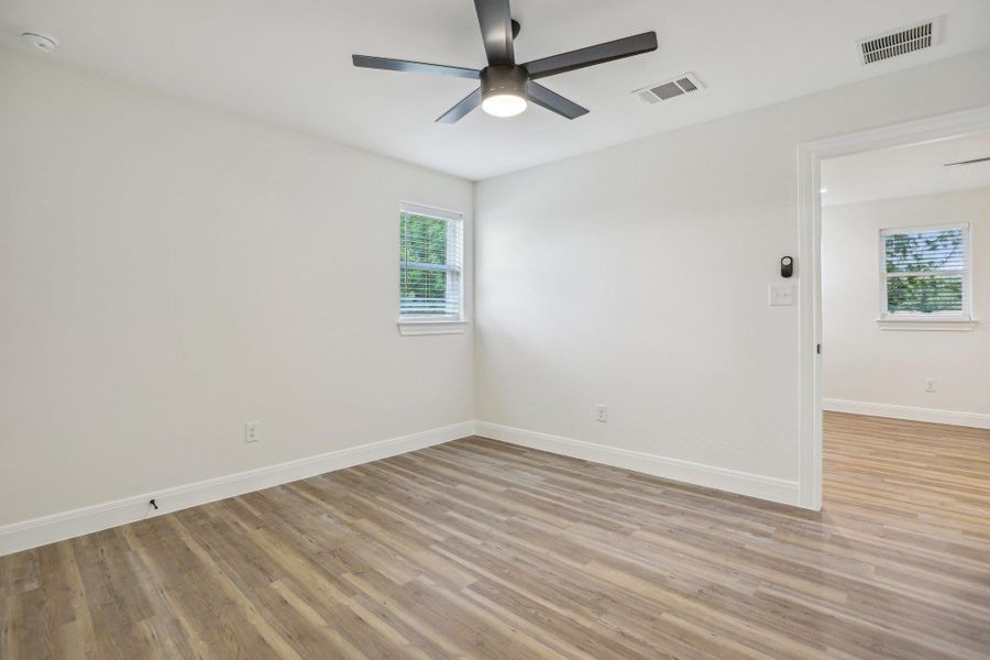 Bedroom 2 featuring light wood-type flooring, visible vents, a ceiling fan, and baseboards