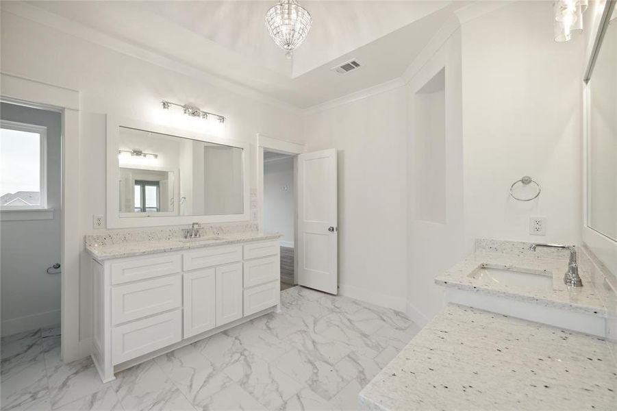 Bathroom with tile patterned flooring, crown molding, vanity, and an inviting chandelier