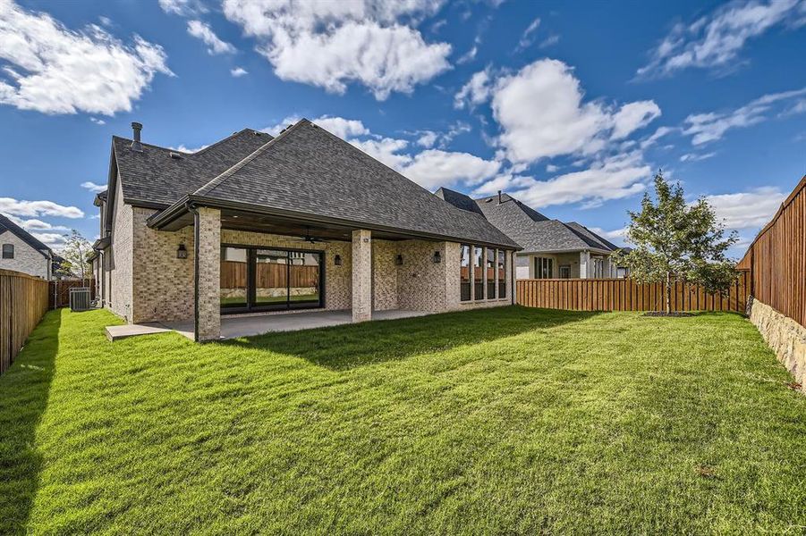 Backyard with large grass area, covered outdoor patio and multi-sliding glass doors