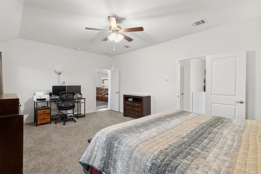 Carpeted bedroom with a desk and ceiling fan