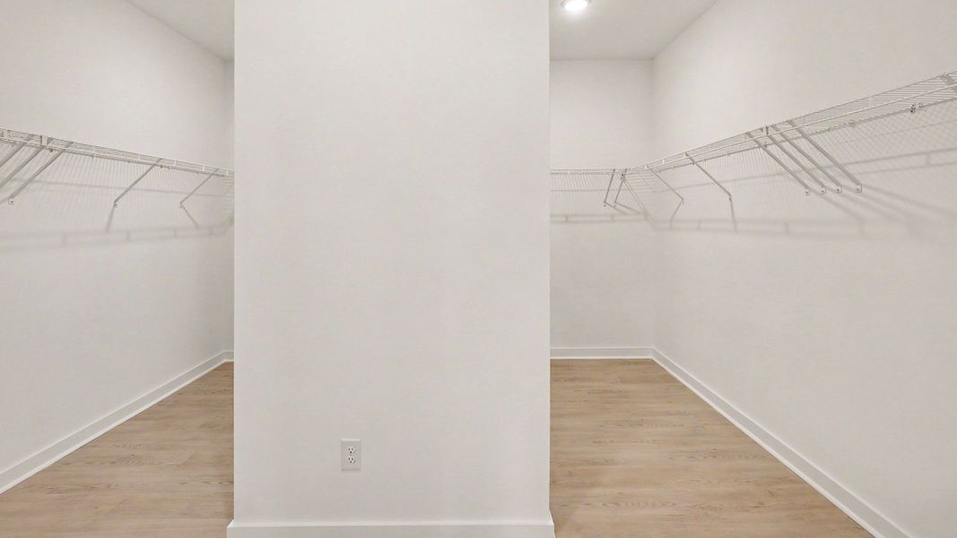 Large primary closet with a dividing wall, accessed via the bathroom, with space for 2 full wardrobes