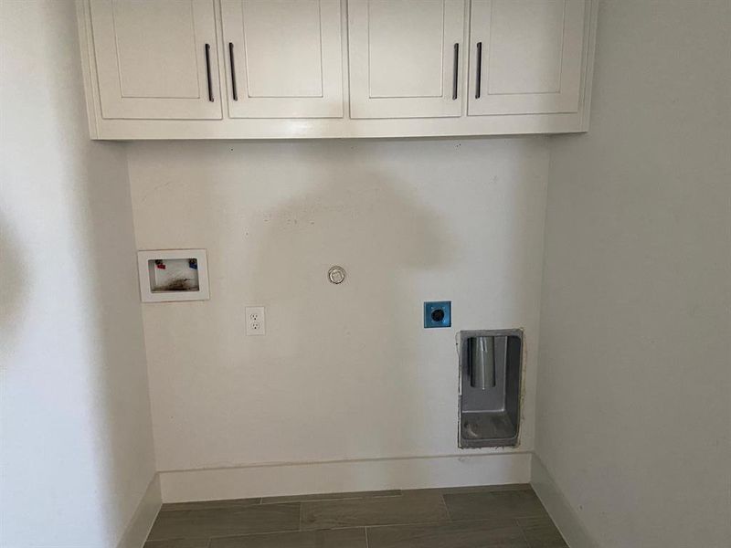 Clothes washing area with hookup for a gas dryer, hookup for a washing machine, cabinets, and hookup for an electric dryer