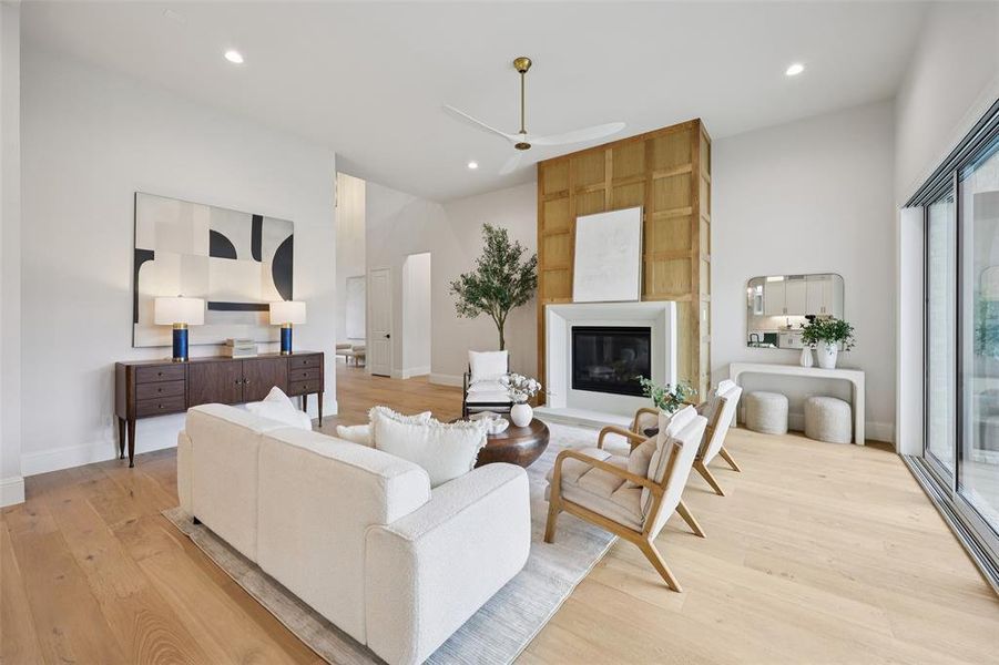 Living room featuring a ceiling fan, light wood finished floors, a large fireplace, and recessed lighting