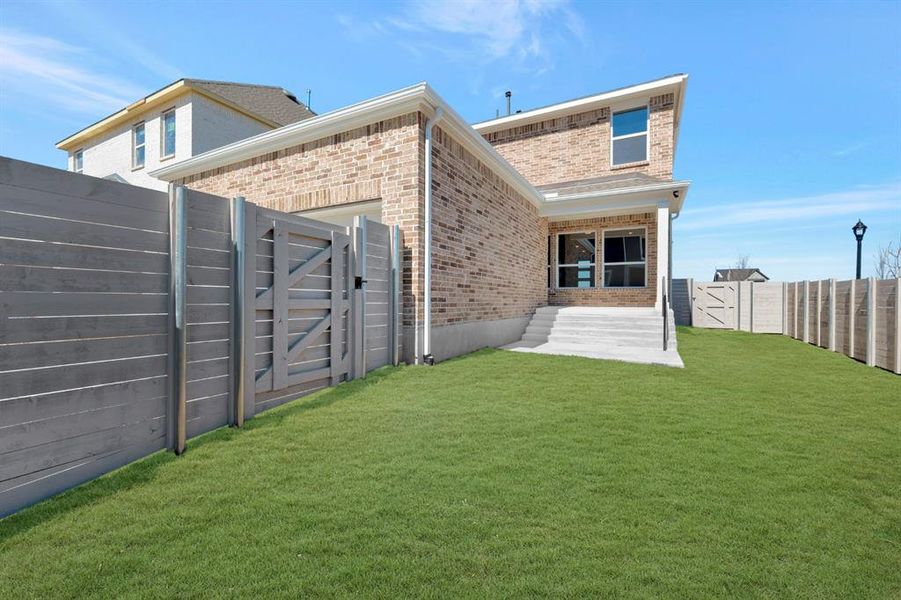 Rear view of property featuring a gate, a fenced backyard, brick siding, and a patio area