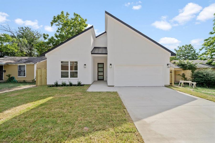 View of front of home with a garage and a front lawn