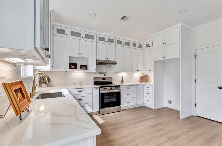 Expansive kitchen with a pot filler, elegant floor-to-ceiling custom cabinetry, and space for a counter-depth refrigerator.