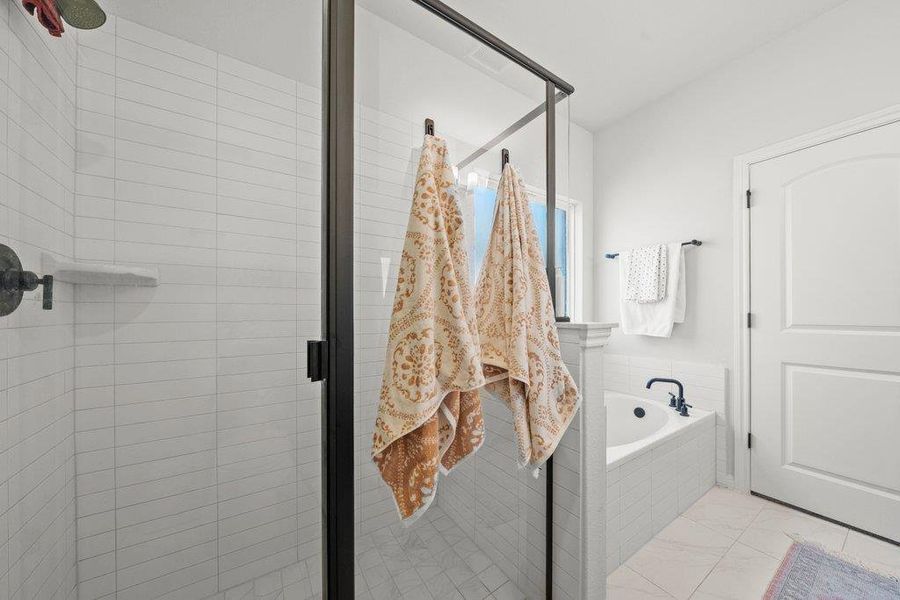 Full bathroom featuring a shower stall, a garden tub, and light marble finish flooring