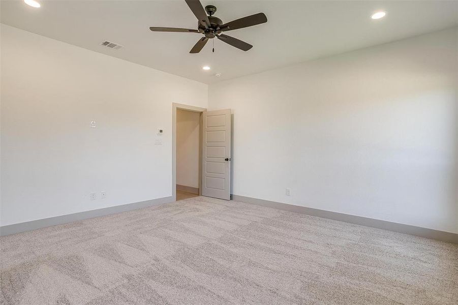 Carpeted empty room featuring ceiling fan