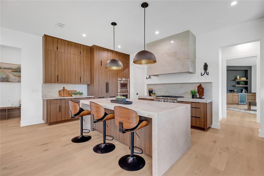 Kitchen featuring light wood finished floors, a center island, tasteful backsplash, a breakfast bar area, and recessed lighting Kitchen featuring light wood finished floors, a center island, tasteful backsplash, a breakfast bar area, and recessed lighting