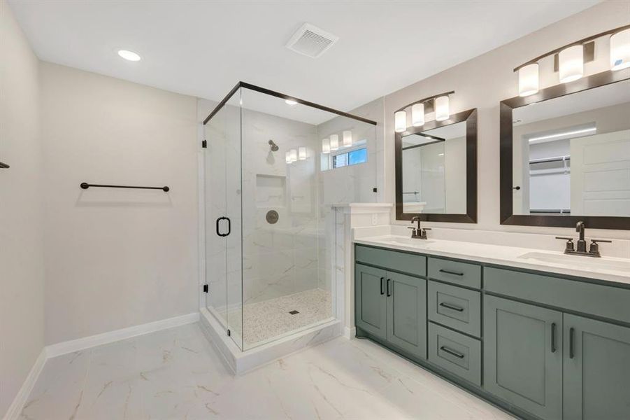 Bathroom with double vanity, a marble finish shower, and light marble finish flooring