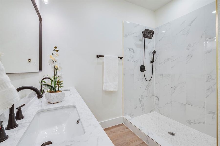 Bathroom featuring vanity, wood-type flooring, and tiled shower