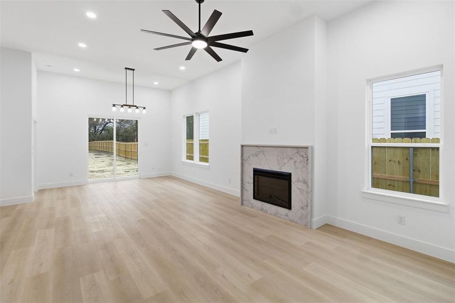 Unfurnished living room featuring light wood-style flooring, a high end fireplace, recessed lighting, and a ceiling fan