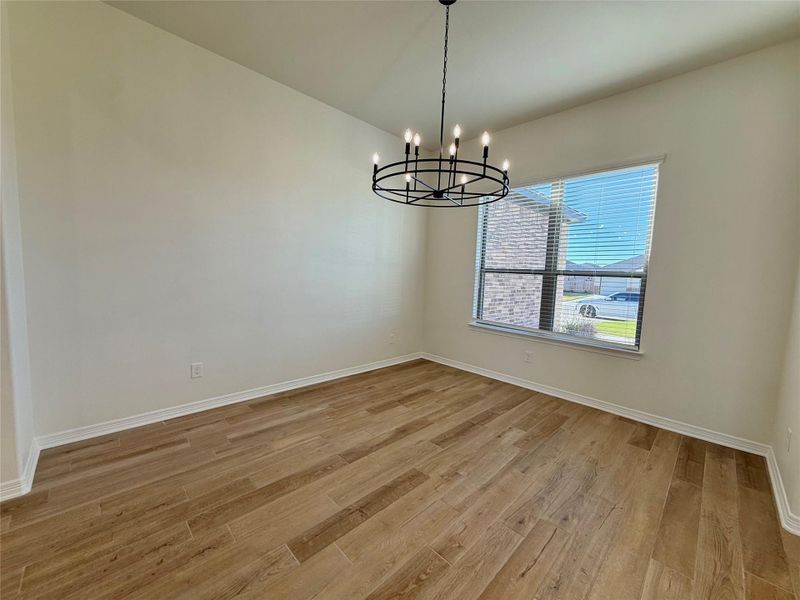 Empty room with light wood-type flooring and a chandelier