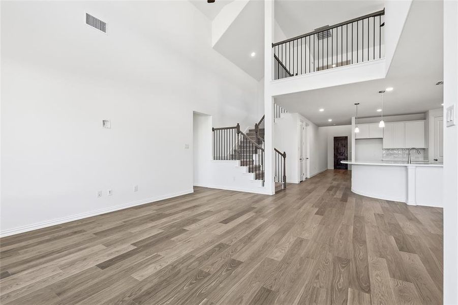 Unfurnished living room with recessed lighting, light wood-style floors, and a high ceiling