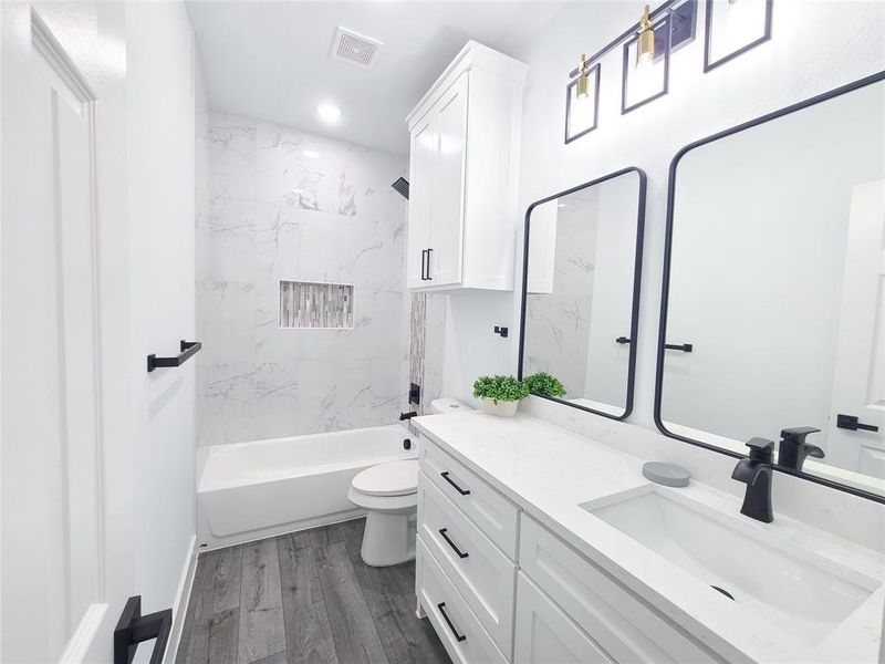 Full bath featuring vanity, shower combination, wood finished floors, and recessed lighting Full bath featuring vanity, shower combination, wood finished floors, and recessed lighting