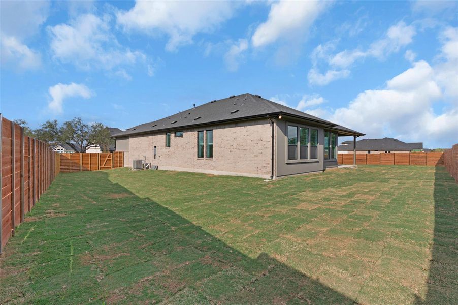 Back of property featuring a fenced backyard and brick siding Back of property featuring a fenced backyard and brick siding
