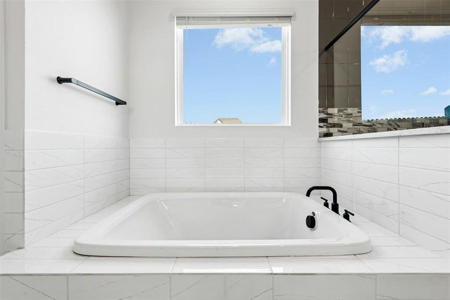 Built-in bathtub featuring a white finish and matte black fixtures