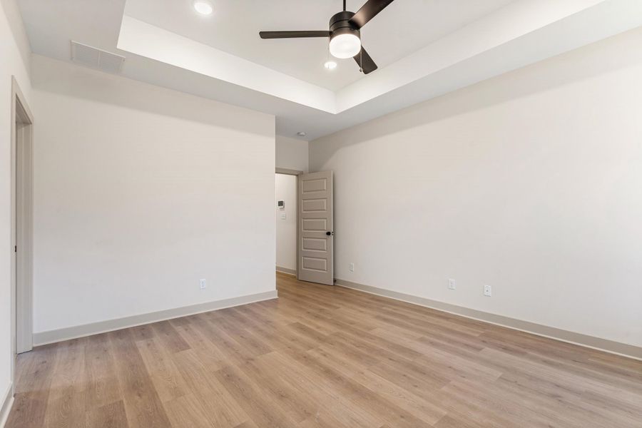 Unfurnished room with a tray ceiling, a ceiling fan, light wood-style floors, and recessed lighting