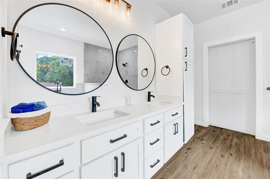 Dual vanities, sleek black fixtures, and elegant lighting. Dual vanities, sleek black fixtures, and elegant lighting.