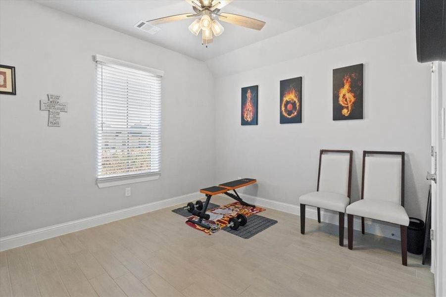 Miscellaneous room featuring ceiling fan, lofted ceiling, visible vents, baseboards, and light wood finished floors