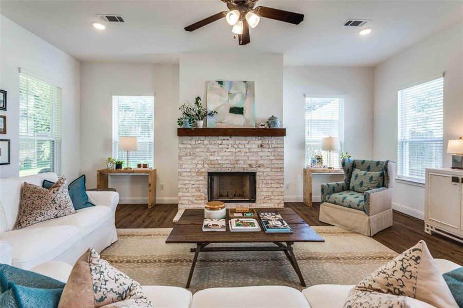 Living room with a fireplace, dark hardwood / wood-style floors, and ceiling fan