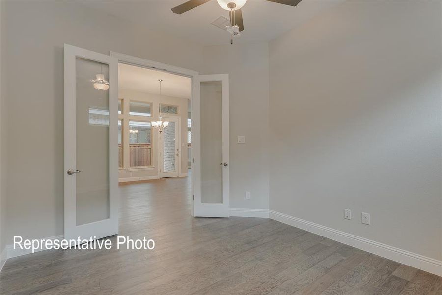 Unfurnished room featuring french doors, wood-type flooring, and ceiling fan with notable chandelier