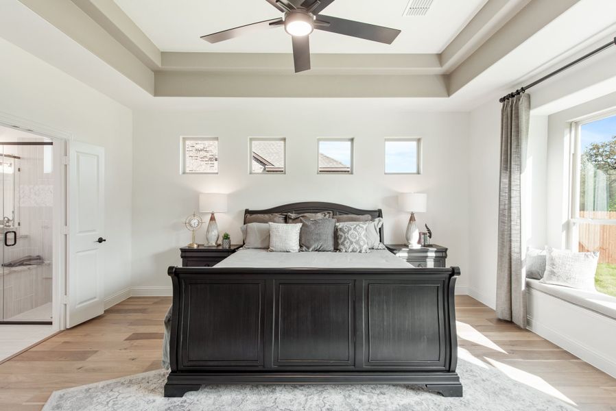 Master bedroom with dark sleigh bed, tray ceiling, ceiling fan, hardwood floors, and window seat Master bedroom with dark sleigh bed, tray ceiling, ceiling fan, hardwood floors, and window seat