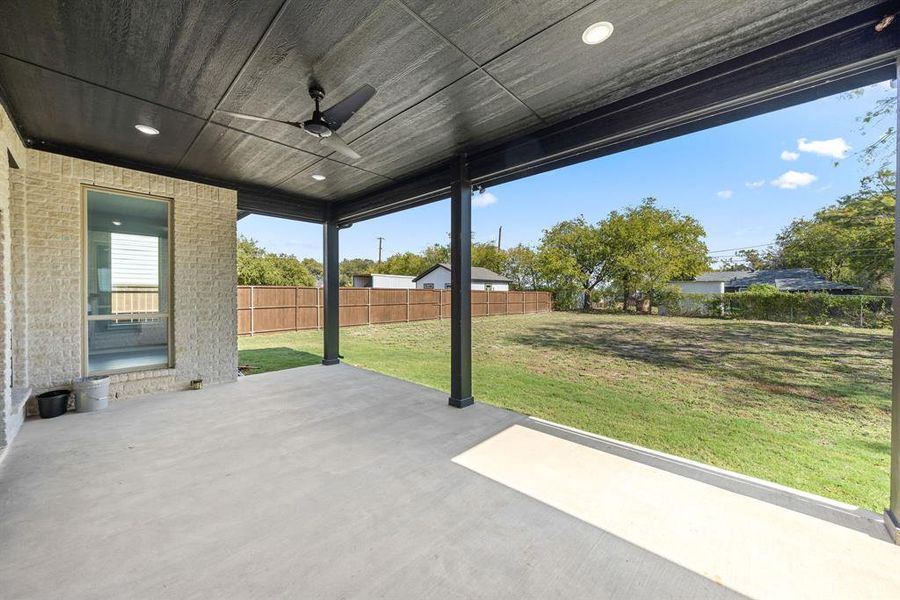 Fenced backyard featuring a ceiling fan and a patio area