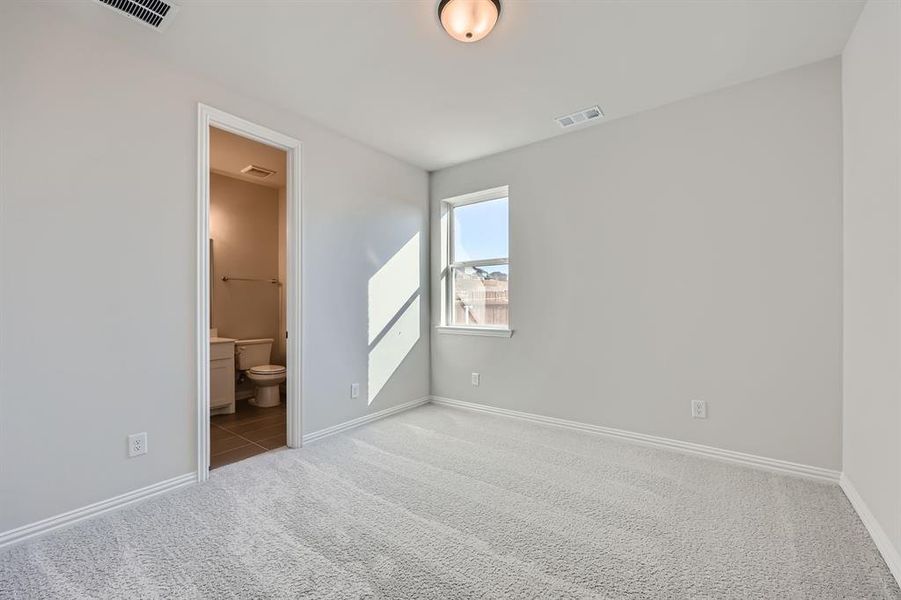 Unfurnished bedroom featuring ensuite bath and light carpet