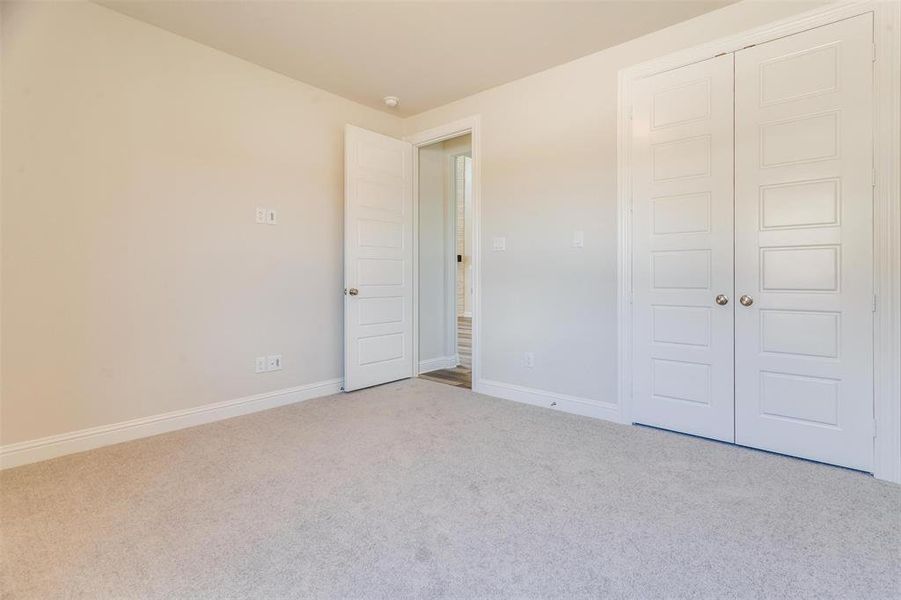 Unfurnished bedroom featuring a closet and light colored carpet