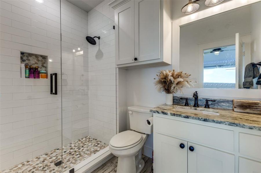 Bathroom with a tile shower, hardwood / wood-style flooring, oversized vanity, ceiling fan, and toilet Bathroom with a tile shower, hardwood / wood-style flooring, oversized vanity, ceiling fan, and toilet