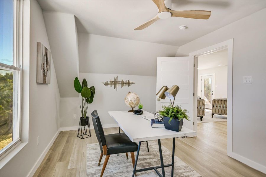 Office area with light wood finished floors, vaulted ceiling, and ceiling fan
