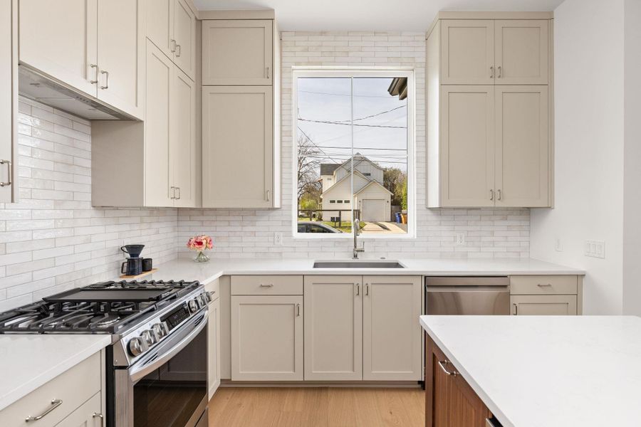 Dual tone kitchen featuring stainless steel appliances, two tone cabinets, light stone counters, and light wood-type flooring Dual tone kitchen featuring stainless steel appliances, two tone cabinets, light stone counters, and light wood-type flooring