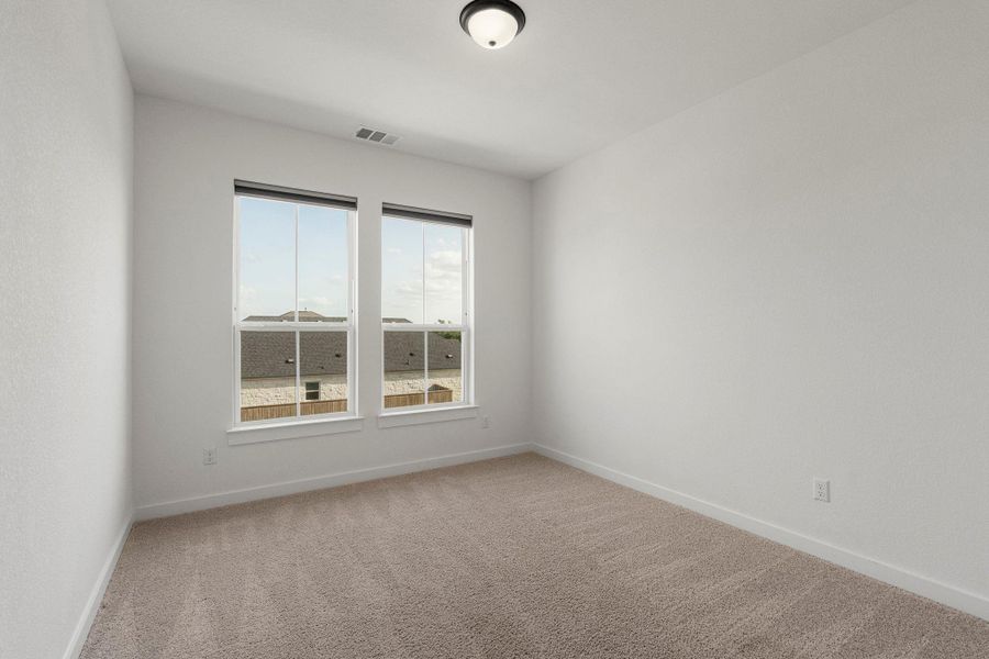 A quiet secondary bedroom offering cozy carpeted floors and neighborhood views.