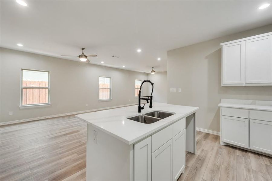 Kitchen with an island with sink, light hardwood / wood-style flooring, sink, and ceiling fan