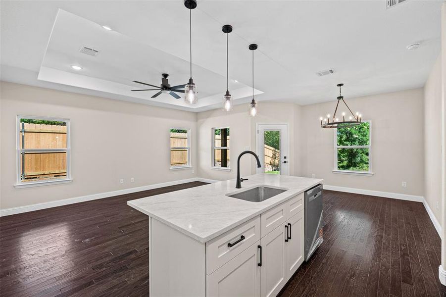 Kitchen island featuring a single-basin sink with a matte black faucet, integrated dishwasher, and white cabinetry with dark hardware