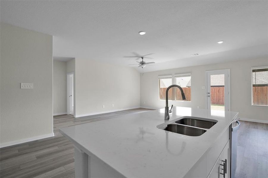 Kitchen featuring white cabinetry, a center island with sink, light stone counters, light wood finished floors, and open floor plan Kitchen featuring white cabinetry, a center island with sink, light stone counters, light wood finished floors, and open floor plan