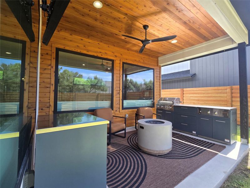 Rich wood planking lines the ceiling of a covered outdoor living space.
