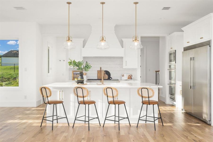 Stunning kitchen with double ovens, built-in Frigidaire side-by-side fridge and freezer set.