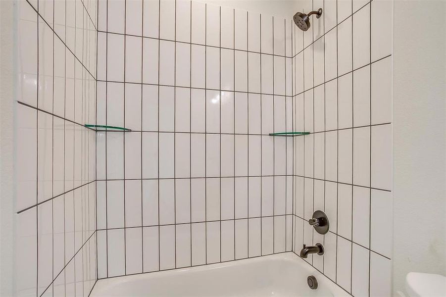 Bathroom with tiled shower / bath and toilet