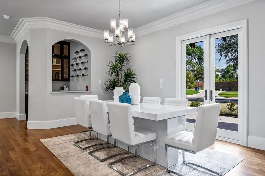 Dining space featuring hardwood / wood-style floors, ornamental molding, french doors, and a chandelier