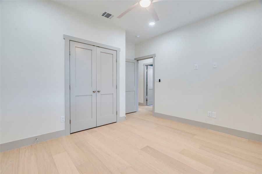 Unfurnished bedroom with light wood-type flooring, ceiling fan, and a closet