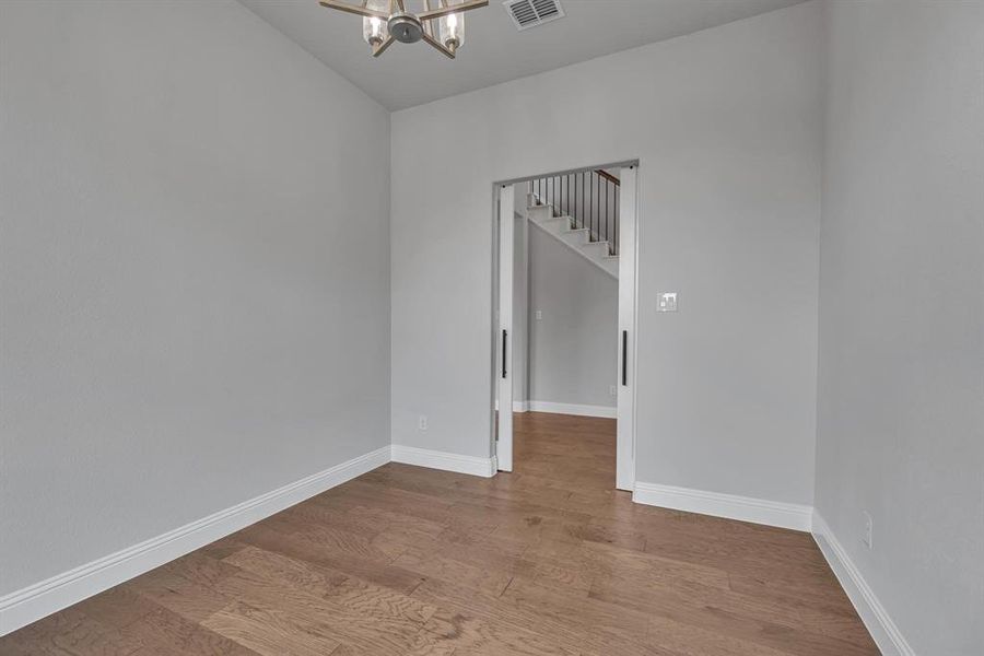 Spare room featuring light hardwood / wood-style flooring and a notable chandelier