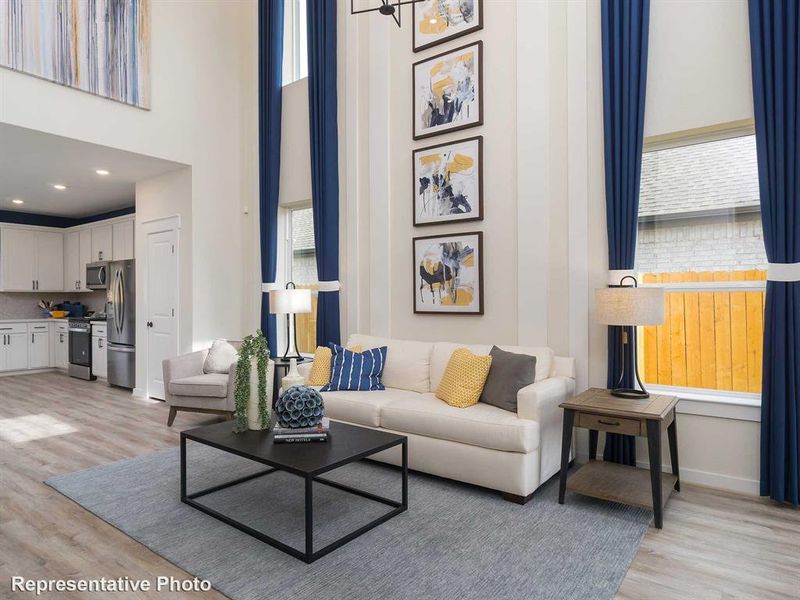 Living room with light wood finished floors, healthy amount of natural light, and a towering ceiling
