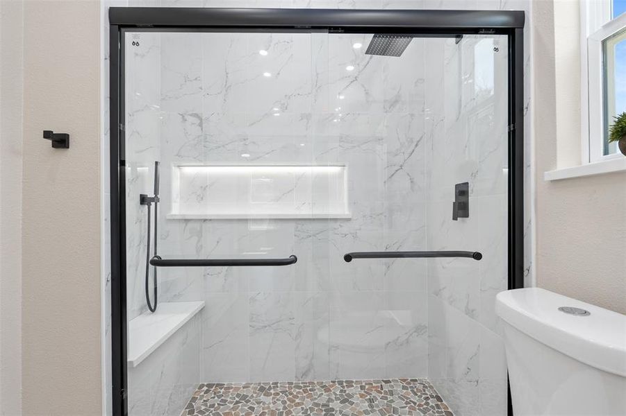Bathroom featuring a marble finish shower and a textured wall