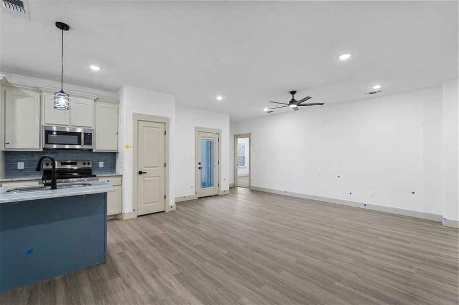 Kitchen with light wood finished floors, visible vents, decorative backsplash, appliances with stainless steel finishes, and a sink