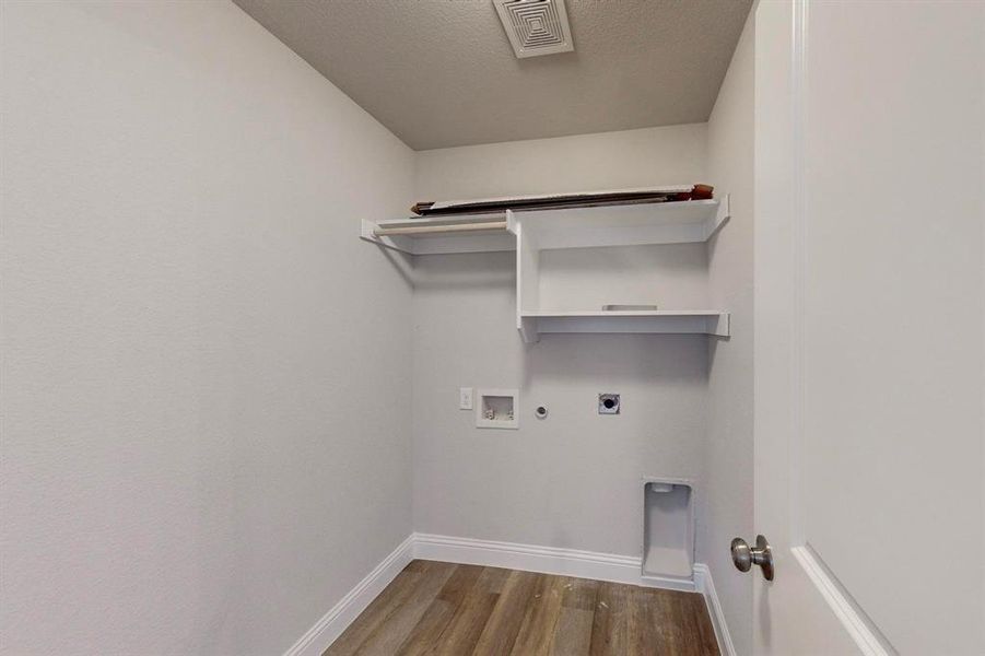 Laundry area with washer hookup, a textured ceiling, hardwood / wood-style flooring, electric dryer hookup, and hookup for a gas dryer